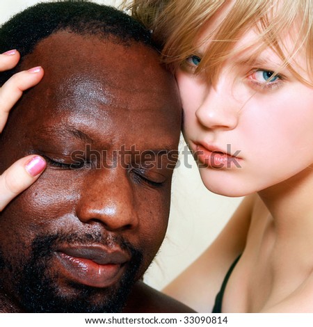 Young beautiful blonde woman embraces a head of the black man