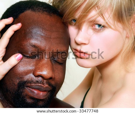 Young beautiful blond woman embraces a head of the black man