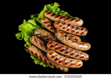 Grilled sausages isolated on black background with salad. Delicious barbecue fast food.
