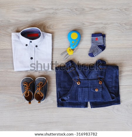 Top view fashion trendy look of baby clothes and toy on the wooden floor, baby fashion concept. Little boy clothes set.