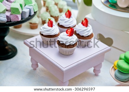 Chocolate cupcakes on a wooden stand as part of sweet dessert table or candy bar. Wedding party. Natural light