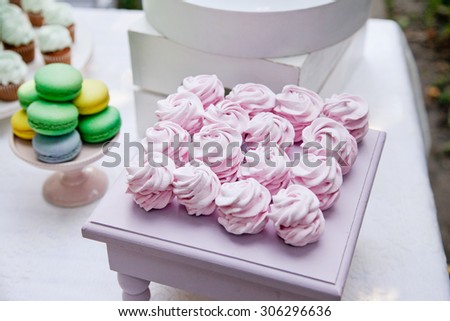 Zefir or marshmallow roses on a wooden stand as part of sweet dessert table or candy bar. Wedding party. Natural light