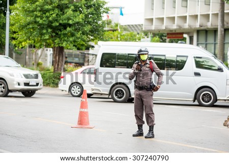 BANGKOK, THAILAND - AUGUST 13, 2015 : Traffic policeman officer works on a busy road. Police regularly direct traffic in busy areas.