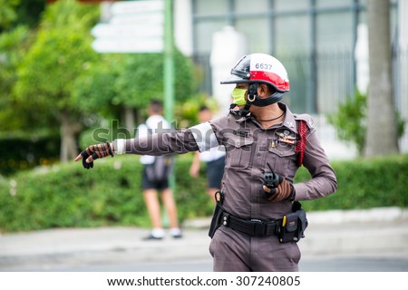 BANGKOK, THAILAND - AUGUST 13, 2015 : Traffic policeman officer works on a busy road. Police regularly direct traffic in busy areas.