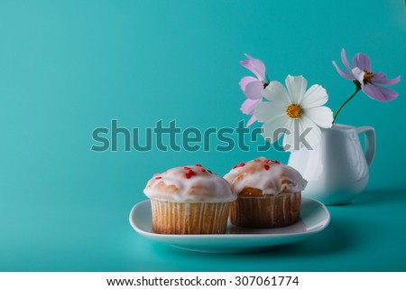 Muffins on saucer with flower. Aqua color background