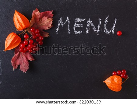 Red fall berries and leaves on black slate background with place to text and word menu