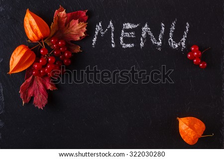 Red fall berries and leaves on black slate background with place to text and word menu