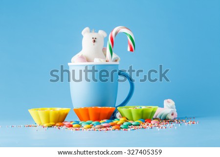Kid decoration. Colored candy and mug with toy on blue background