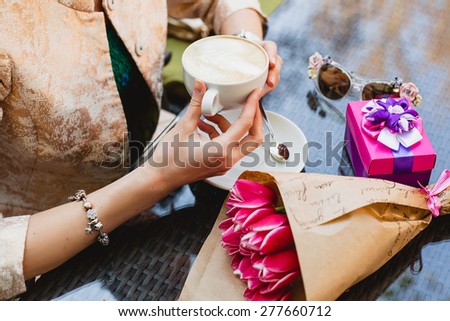 young stylish woman, fashion sunglasses, sitting in cafe, holding drinking cup cappuccino, tulips, happy birthday party, boho outfit, europe vacation, romantic dinner, gift, close up, detail