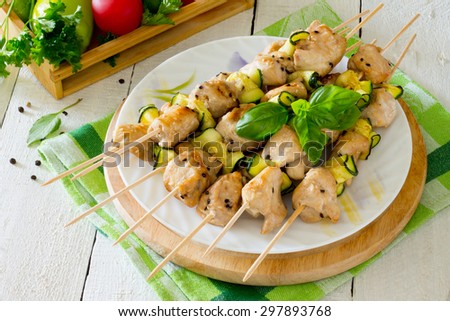BBQ chicken kebabs with zucchini on a white wooden background