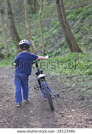 young six year old boy pushing his bike