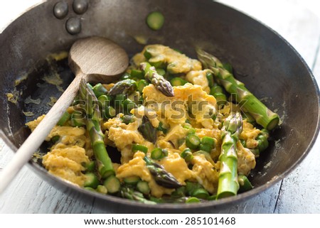 Green asparagus with egg in a frying pan.