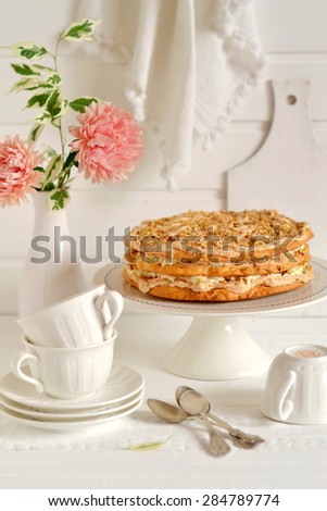 shortbread cake with nuts and meringue on a stand on a light wooden background