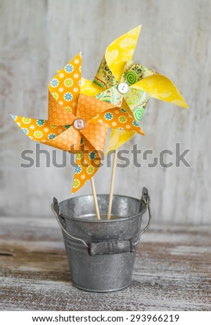 paper homemade pinwheel vintage metal bucket on a light wooden background