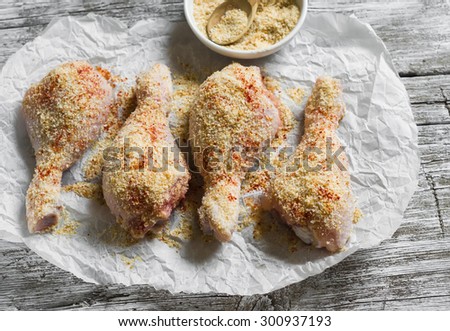 raw chicken legs ingredient for fried chicken legs with paprika and bread crumbs on a light wooden background