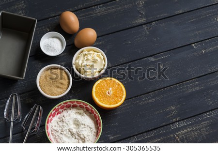 raw ingredients - flour, eggs, butter, sugar, orange - to cook orange cake. Ingredients for baking. Ingredients for the dough. On a dark wooden surface