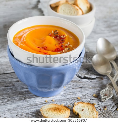 pumpkin soup in ceramic bowls on a light wooden background