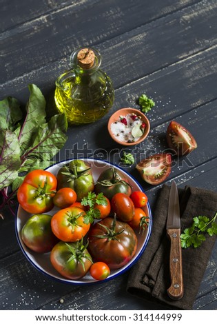 fresh tomatoes, garden herbs and olive oil on a dark wooden surface
