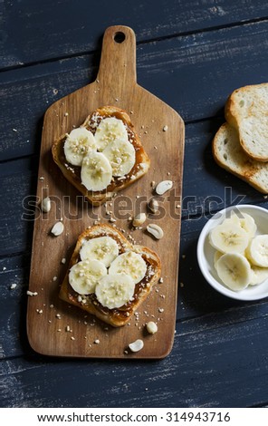 sandwich with peanut butter, banana and peanuts, served on the Board, on a wooden surface