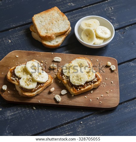 sandwich with peanut butter, banana and peanuts, served on the Board, on a wooden surface