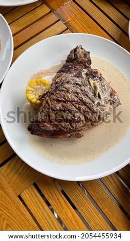 The T-bone steak is a crosscut from the front of the short loin and contains a strip of top loin and a smaller chunk of tenderloin. Considered one of the highest qualit Stock foto © 