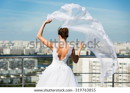 Bride with bridal veil waving in the wind against the blue sky