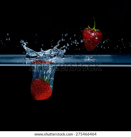 Strawberry falls into water. Strawberries in the air. Splash water.