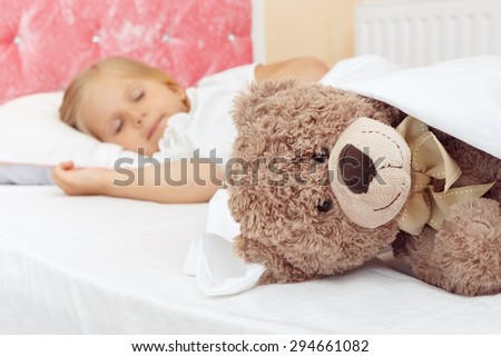 Adorable little girl sleeping in bed with her teddy bear