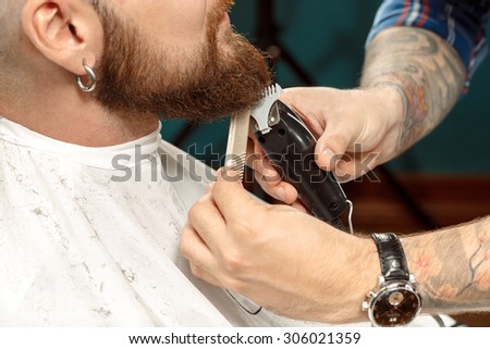 Handsome man getting his beard shaved in a barber shop