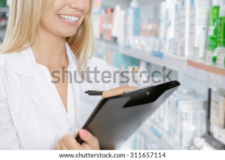 Beautiful pharmacist accounting the product in drugstore