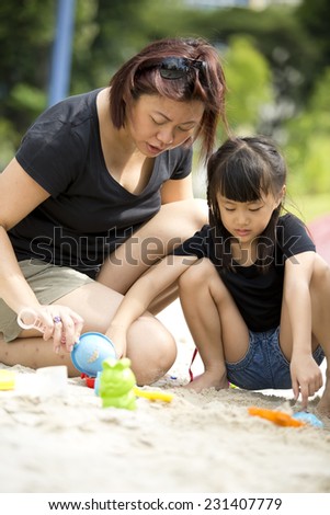 Asian mother and daughter playing sand in park