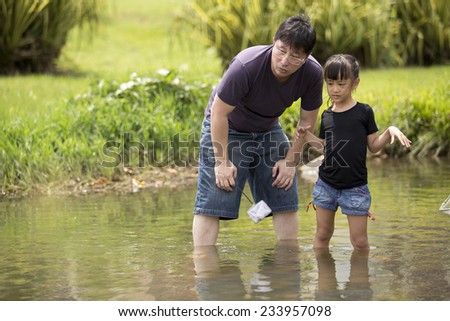 Asian father and daughter bonding time catching fishes in river