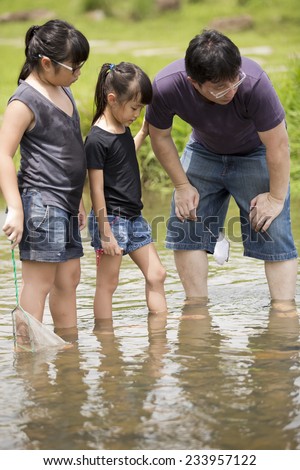 Asian father and daughter bonding time catching fishes in river