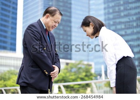 Asian senior businessman & young female executive bowing to each other