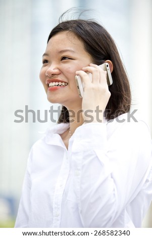 Asian young female executive smiling and talking on phone