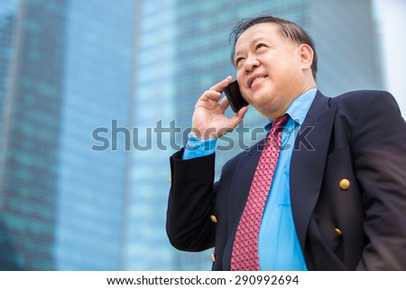 Asian senior businessman in suit using smart phone