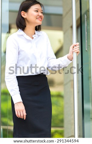 Young Asian female executive coming out of a building
