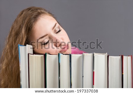 Bored of the learning. Young female got bored of reading and sleeps on the tons of books