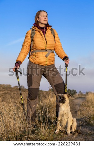 Hiking team. Female backpacker and her dog stay on trail and observe the surrounding landscape.