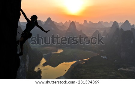 Elegant female extreme climber silhouette against the sunset over the river. China, typical Chinese landscape with mountains and river