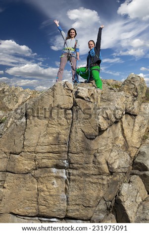 Group of two happy female climbers that are just conquered the summit stays over the rocky wall