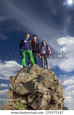 Group of climbers stays on the pointed cliff. Family of father and two daughters stays on the rocky cliff that sharply breaks to the abyss