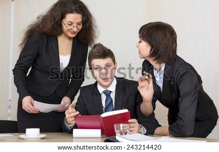 Group of business people discuss working schedule Three young businesspeople, one male and two females, are having discussion with diary, charts and other office supplies