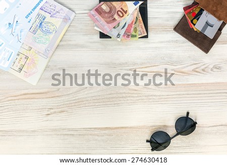 Back from vacation. Pocket essential items travel topic background wood desk passport exotic foreign cash credit cards sunglasses stylish entry stamps boarding pass from above view wooden texture