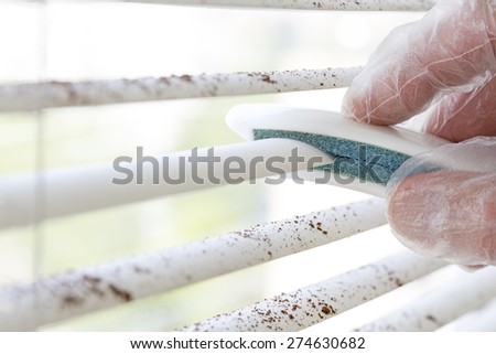 Spring cleaning, Dirty sections of white sun blinds and hand of worker who clean it up with special tool rubber protection glove window glass cleaning