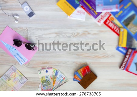 Desk of mature voyager.
Travel background with essential tourist items on wooden desk passport international with entry stamps and visas exotic currency credit card many maps sunglasses from above