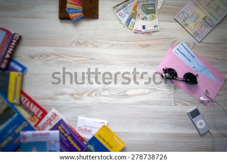 Desk of mature voyager.\
Travel background with essential tourist items on wooden desk passport international with entry stamps and visas exotic currency credit card many maps sunglasses from above