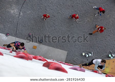 Speed track of Climbing competitions and two sportsmen beginning run. Focus on closer holds, people blurred. National Climbing Championship, Speed climbing final. Dnepropetrovsk, Ukraine, May 23, 2015