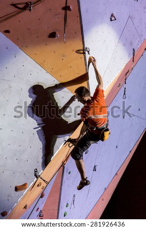 Male athlete makes hard move on climbing wall. National Climbing Championship, Lead climbing finals. Dnepropetrovsk, Ukraine, May 23, 2015