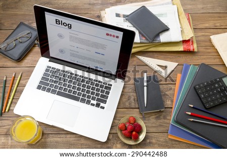 Vacation entertainment concept. \
Handcrafted countryside style wooden desk items in creative disorder laptop computer internet page on screen color pencils booklets plate strawberry glass orange juice